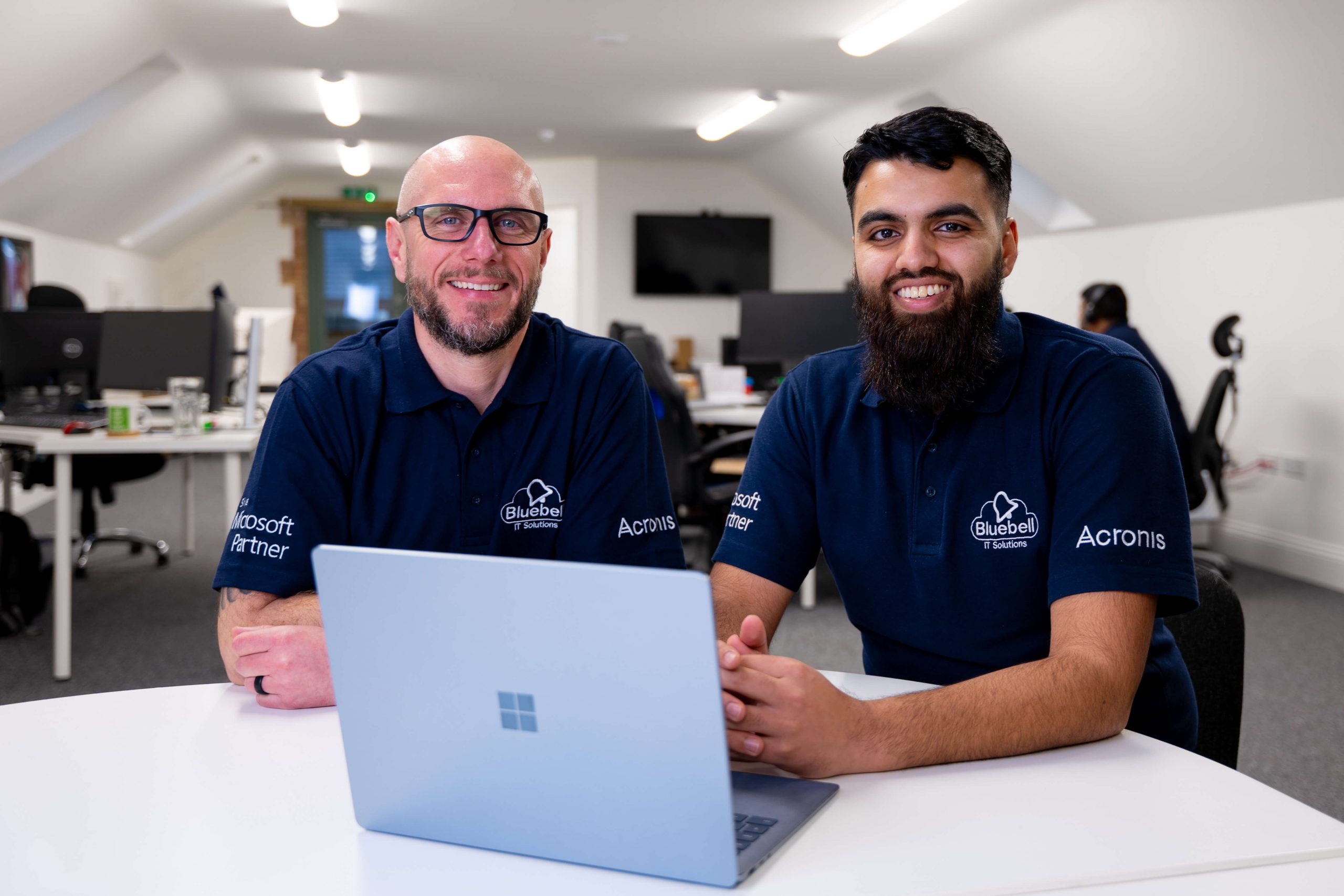 Two IT support professionals from Bluebell IT Solutions smiling in a modern office environment in Northampton